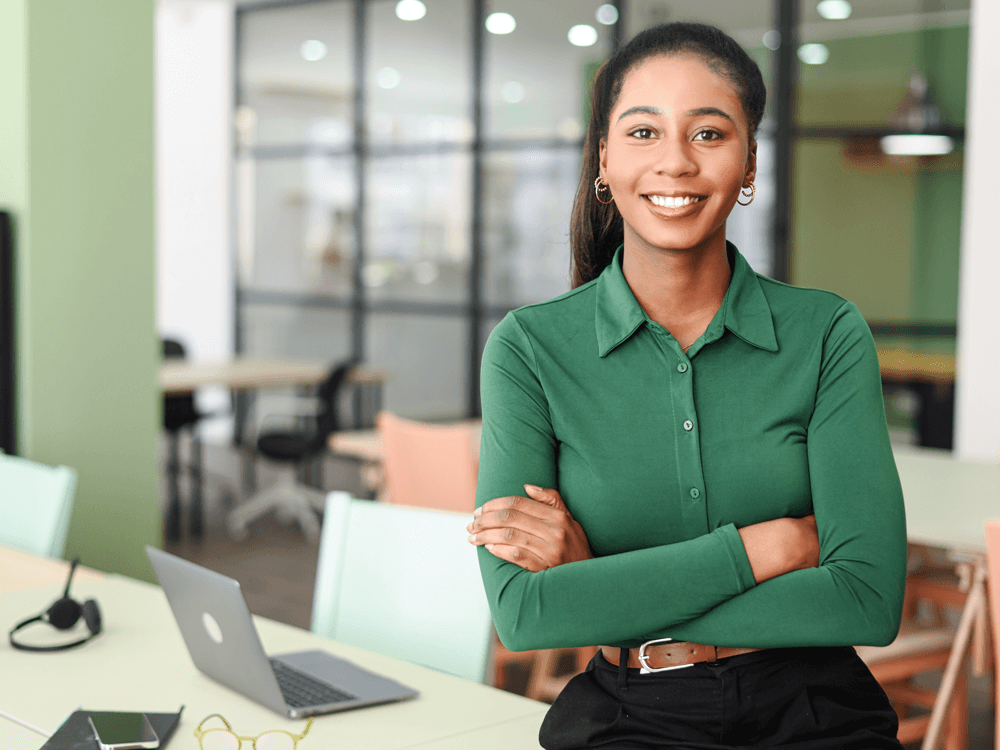 african american woman wearing green blouse smiling by her office desk